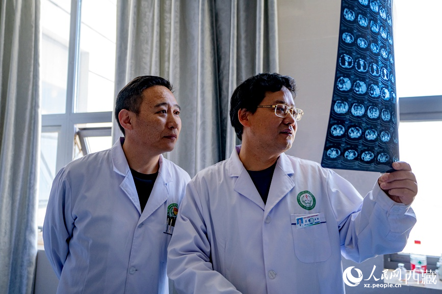 吴维（右一）和强巴旦增（右二）在查看患者的影像资料。人民日报记者 徐驭尧摄