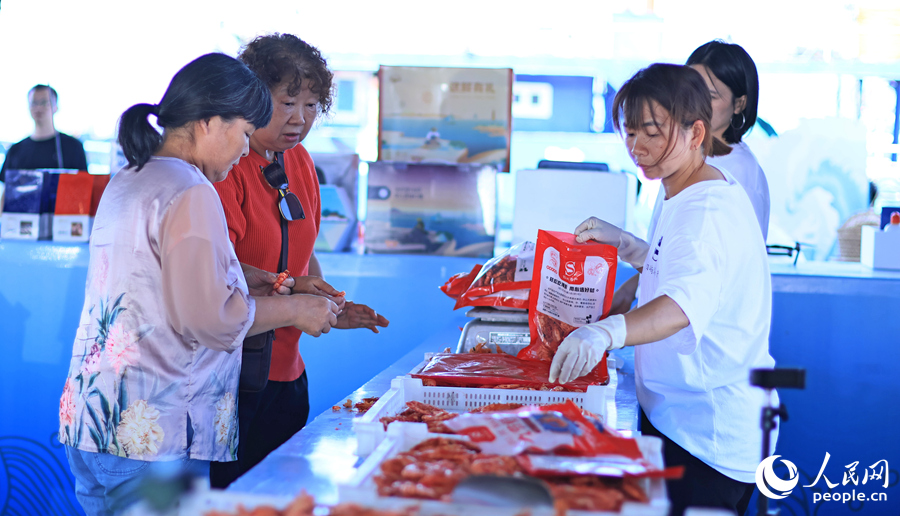 游客在澳角村采购当地海鲜加工产品。人民网 李昌乾摄 游客在澳角村采购当地海鲜加工产品。人民网 李昌乾摄