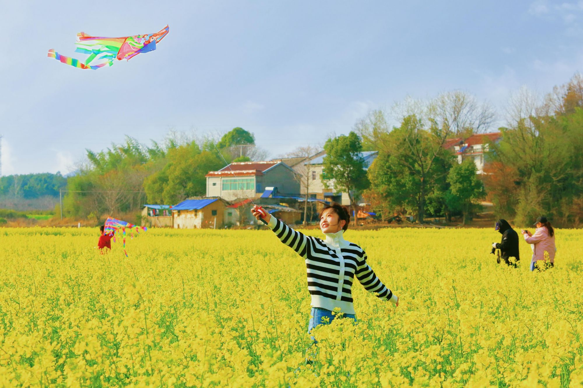 在安徽省太湖县，游客在油菜花田中放风筝。刘辉摄