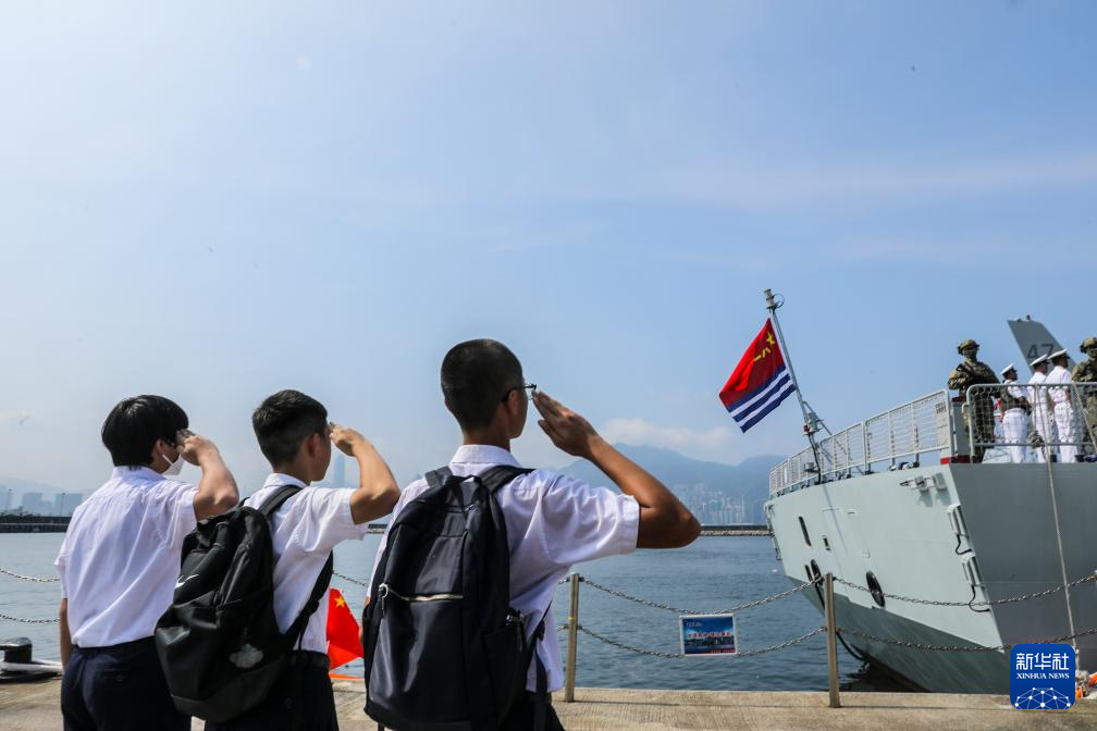 7月7日,湛江舰即将驶离昂船洲军营码头,三名香港福建中学的学生向悬挂在舰尾的海军军旗敬礼。新华社发(冯丽 摄)