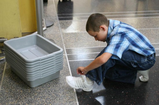 2006年8月10日,在美国首都华盛顿里根机场,一名小男孩在脱鞋准备进行安检。 新华社记者吕明响摄