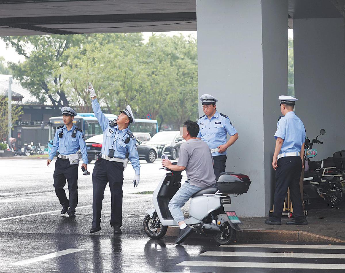 7月10日，北二环积水潭桥下，执勤交警提醒一位“闯红灯”的骑行者通过路口应依照非机动车信号灯的指示。 摄影/新京报记者 王贵彬