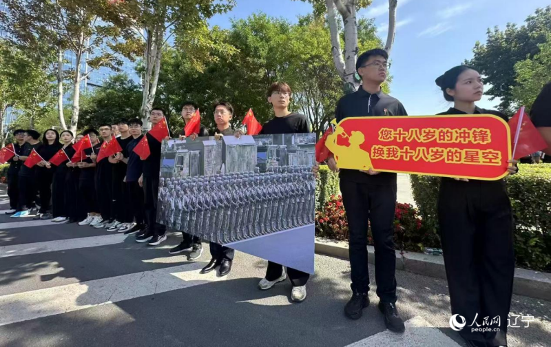 沈阳市人民广场上，大学生们手持阅兵的图片，告慰英烈。人民网记者 周颂雪摄