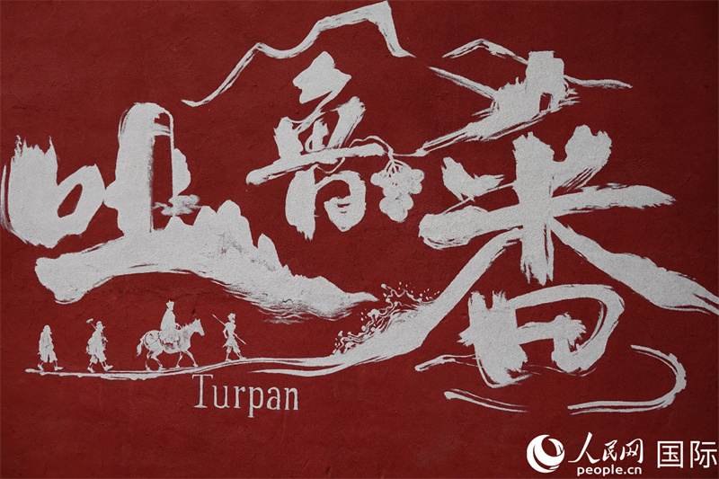 一幅绘有吐鲁番及其中文名“吐鲁番”的热浪壁画，以及中国古典名著《西游记》中发生在吐鲁番的著名场景。人民网记者 王禹蘅摄